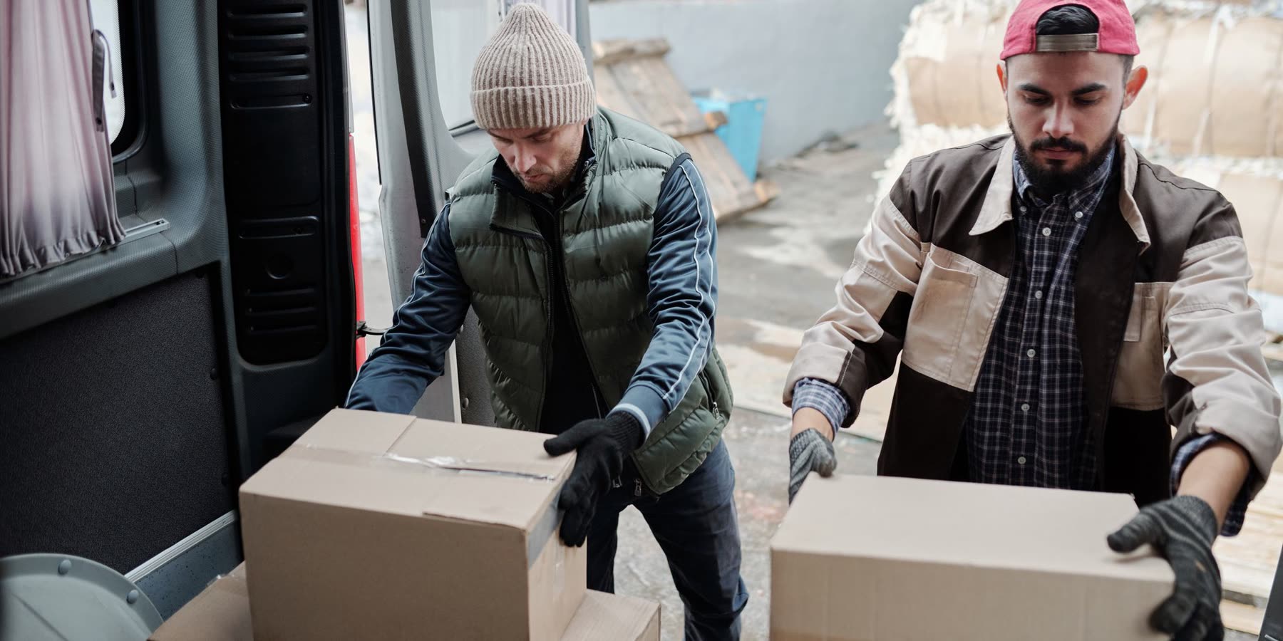 Two operatives loading boxed equipment into a delivery van at the dispatch bay