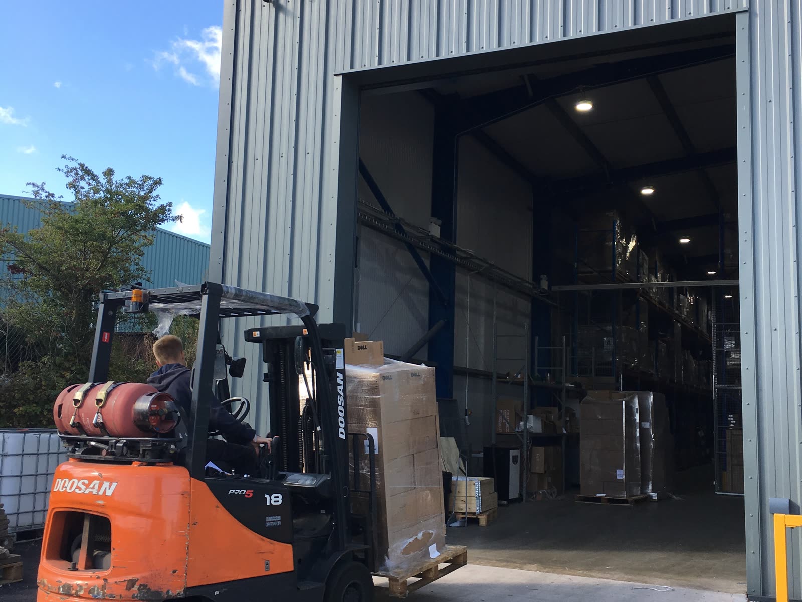 A forklift loading a shrink-wrapped pallet of new IT hardware into the Greensafe warehouse