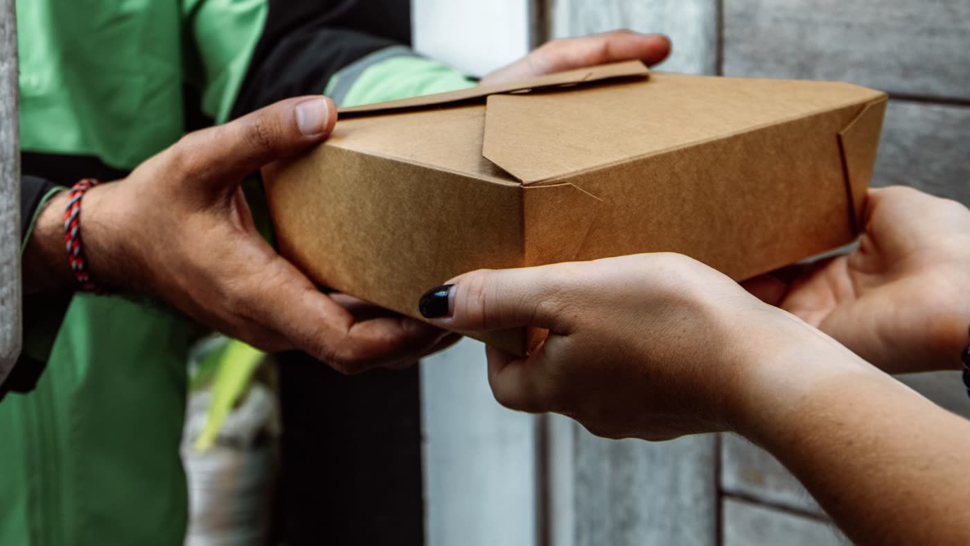 A parcel being handed over on a doorstep at the end of a last-mile delivery