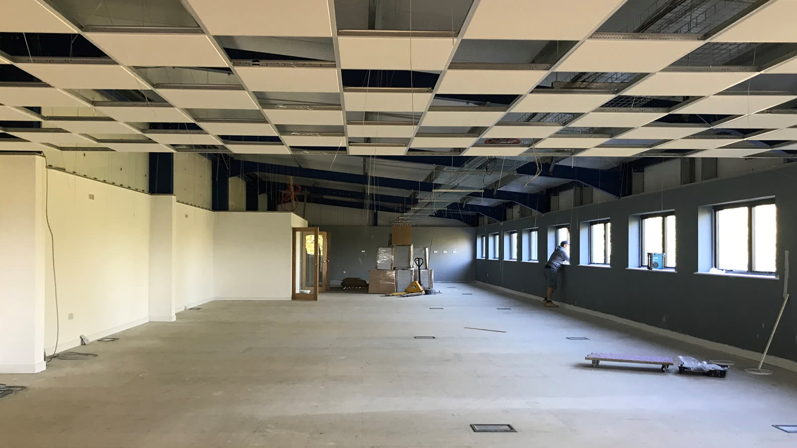 The same room part-finished — suspended ceiling grid installed, partitions built and painted