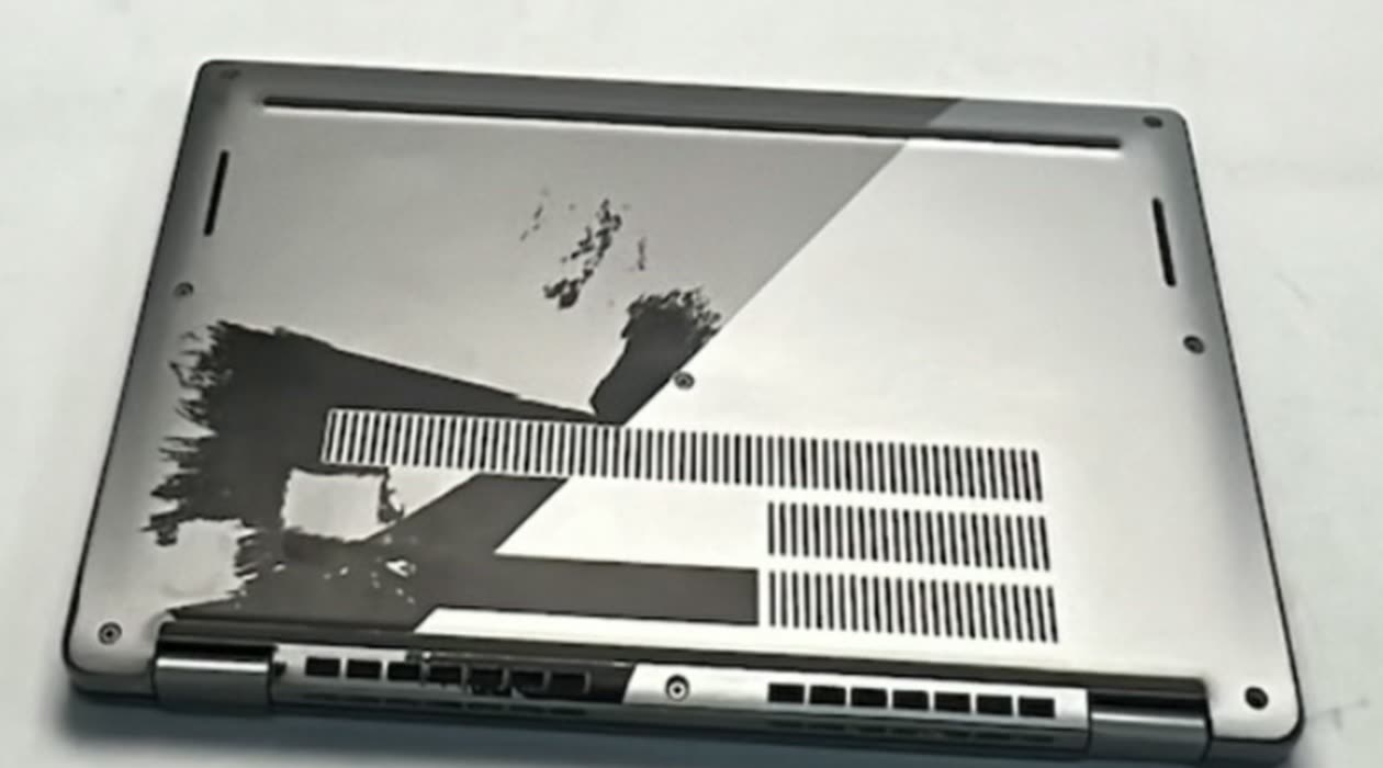 A laptop base, half with paintwork worn away and half vinyl wrapped, in a single photograph