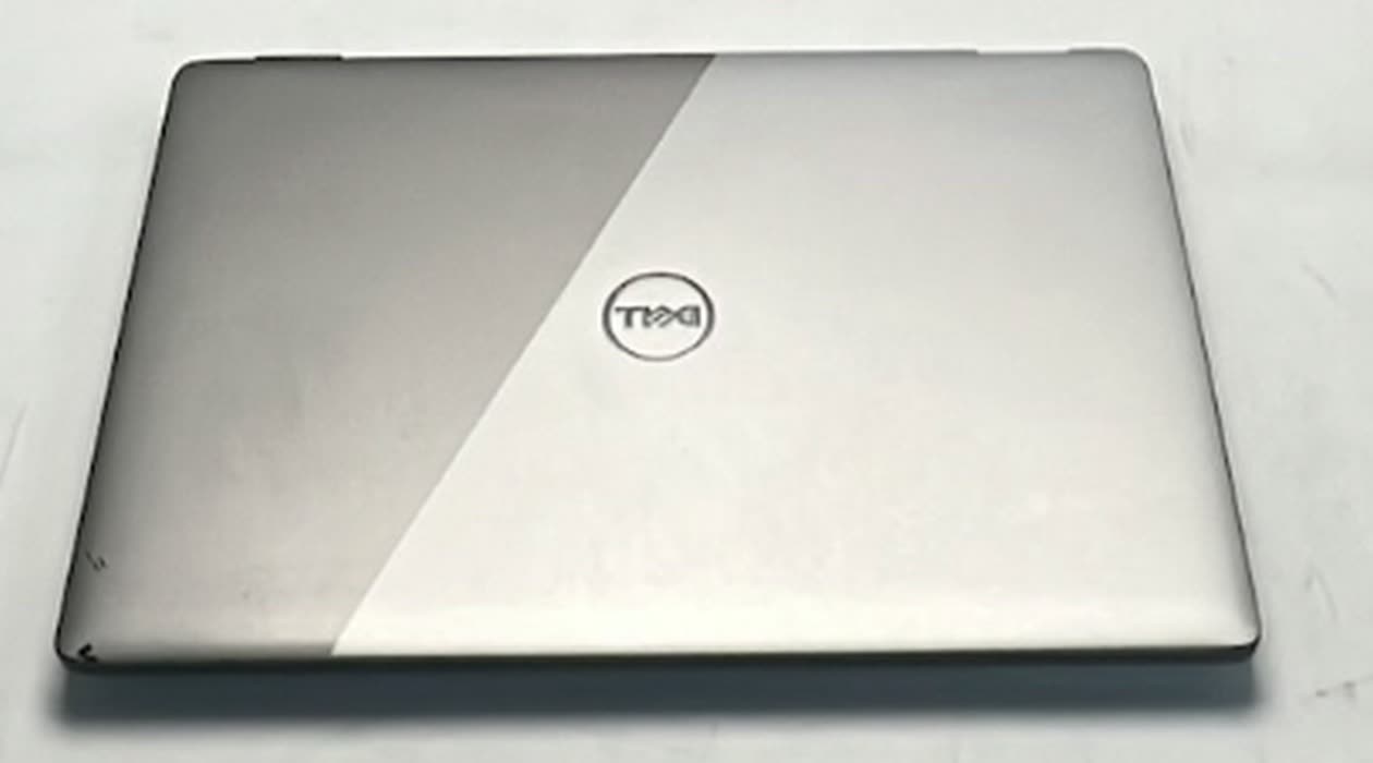 A laptop lid, half worn paintwork and half vinyl wrapped, in a single photograph
