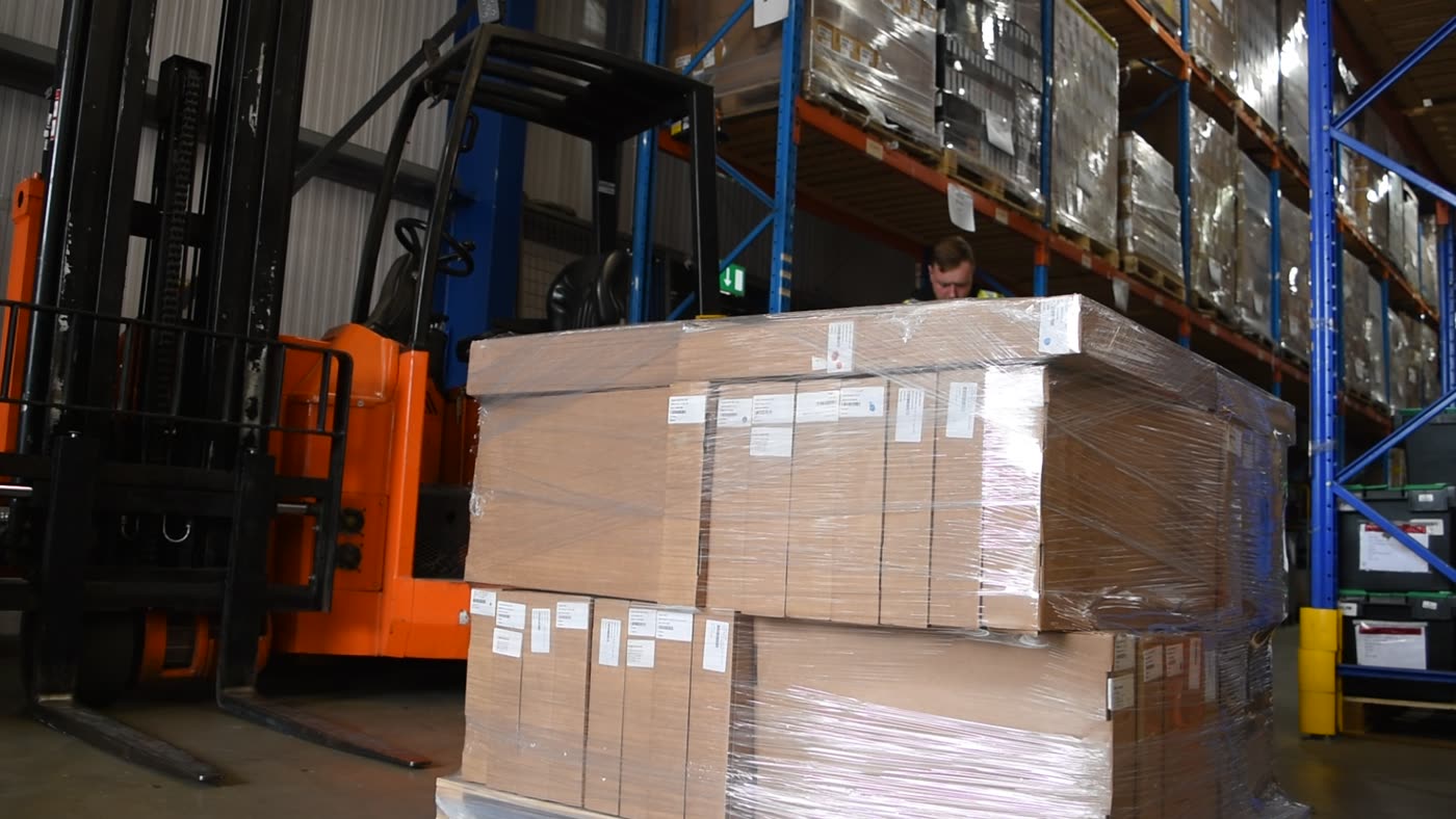 A forklift placing palletised stock into racking