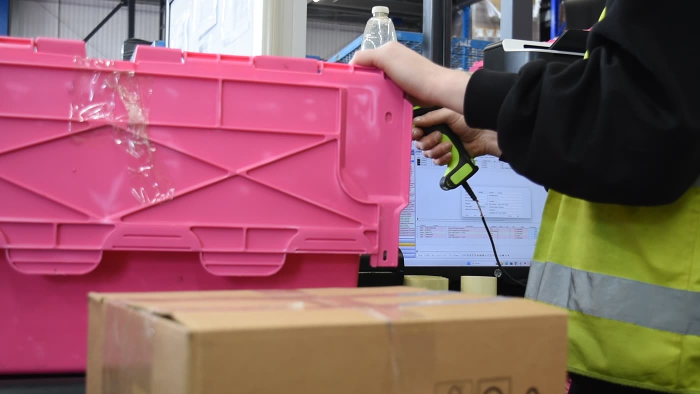 A handheld scanner reading the barcode on a stock tote